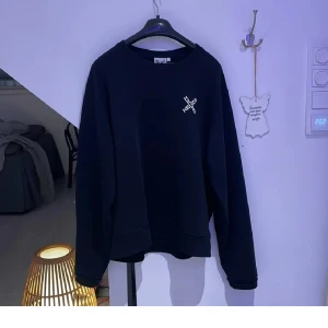 Kenzo tröja - Säljer en stilren svart sweatshirt från Kenzo i mycket bra skick. Den har en enkel design med en liten vit logga på bröstet.