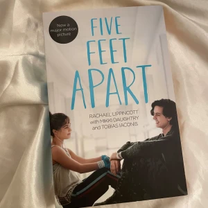 Five Feet Apart bok på engelska  - Säljer boken 'Five Feet Apart' av Rachael Lippincott, Mikki Daughtry och Tobias Iaconis på engelska. Perfekt för dig som gillar romantiska berättelser med en twist. Boken är i gott skick och har ett fint omslag med karaktärerna från filmen. Boken är på engelska och i helt nytt skick då den aldrig blivit läst. Perfekt för en mysig läsning eller som present! 📚🇬🇧