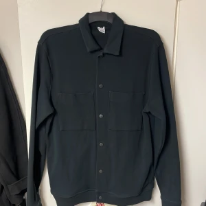 Blå overshirt - Säljer en blå overshirt från ett märke som kallas ”Visual Clothing Project”. Den passar bra på kroppen och har storleken M. Den är perfekt tjocklek och värmer bra men inte för mycket. Overshirten har knappar och fickor. Hör gärna av er vid frågor!🤝💯😁