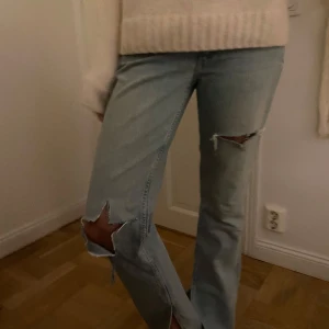 Ljusa jeans med slitningar - Säljer ett par ljusa jeans i mycket bra skick. De har en straight passform och coola slitningar på knäna för en avslappnad look.