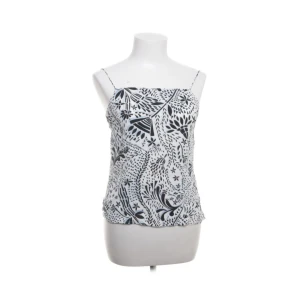 Svart vit/blå mönstrad linnetopp - Snygg svartvit linnetopp med tunna axelband och ett unikt bladmönster. Perfekt för sommardagar eller en avslappnad kväll. Toppen är i ett lätt och luftigt material som gör den bekväm att bära. Passar bra till både jeans och kjol!
