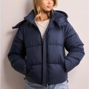 Blå vinterjacka - Säljer denna jättefina vinterjackan från Nelly som är helt slutsåld, påminner väldigt mycket om ralph lauren jackan! Helt oanvänd med prislappen kvar!