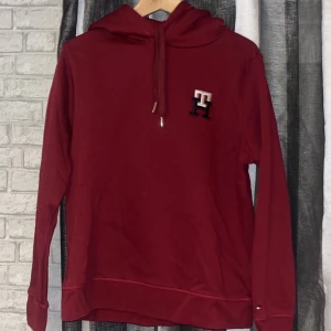 Tommy hilfiger hoodie - Vinröd tommy hilfiger hoodie knappt använd super bra skick. I storlek M. Både killar och tjejer kan använda denna