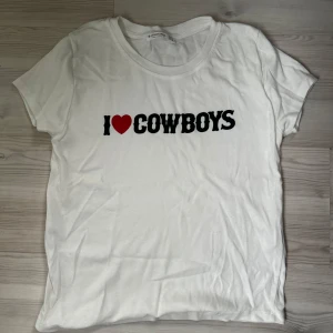 Vit t-shirt med 'I ❤️ Cowboys' tryck - Säljer en vit t-shirt med 'I ❤️ Cowboys' tryck. T-shirten är kortärmad och i mjukt bomullsmaterial. Passar perfekt till jeans eller shorts. Skriv gärna om du är intresserad innan du köper 🫶