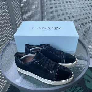 Svarta sneakers från Lanvin - Säljer ett par snygga svarta sneakers från Lanvin i mycket bra skick. Skorna har en glansig finish på tån och snörning framtill. Använda fåtal gånger. De kommer med originalkartong, kvitto och extra snören🧾👞. Storleken uk 9 som motsvarar storlek 43/44 passar även dig med 42 om man lägger ner sula. Perfekta för både vardag och speciella tillfällen. frågor eller annat skriv i dm. 