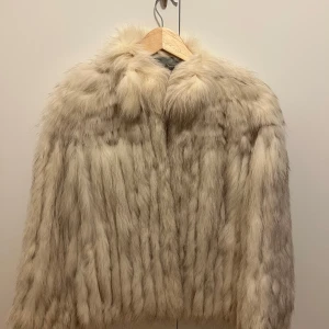 Vit pälsjacka från Saga Fox - Säljer en superlyxig vit pälsjacka från Saga Fox. Den är perfekt för vintern och har en mjuk och fluffig päls. Jackan är i mycket bra skick och ger en elegant look. Storlek 36/38