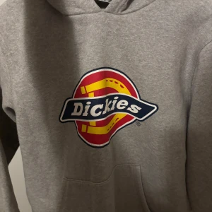 Grå hoodie från Dickies - Säljer en grå hoodie från Dickies i mycket bra skick. Inte mycket använt då den blev för kort i armarna på mig😊