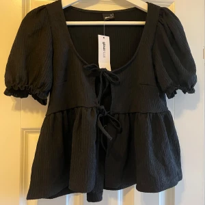 Blus med knyttning - Säljer svart blus med knytning i fram🖤 Jag har inte fått någon användning för den, därav så sitter prislappen fortfarande kvar. Hör av er för fler bilder eller frågor🫶🏻