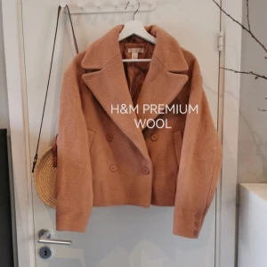 H&m premium skepparkappa kappa ull wool 38 - Vad: H&M PREMIUM trend ullkappa i fluffigt Material. Teddy look. Mörkbeige.  Material: 74% wool 26% polyamid. Foder 100% polyester  Storlek: 38  Skick: Mycket fint skick utan defekter  Mått: bredd 54 cm , höjd 56 cm , ärm från hals 78 cm