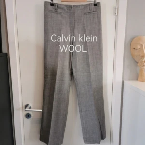 Calvin klein ull wool lowwaist low waist kostymbyxa 40/42 - Vad: Calvin klein grå kostymbyxa med vida långa ben. Superfin 2000s y2k stil. Låg midja. Stretch.  Storlek: 46. Skulle säga mer Storlek 40/42. Se mått. Måtten angivna utan stretch.  Mått: midja 39 cm, hela byxans längd 104 cm, beninnerlängd 78 cm  
