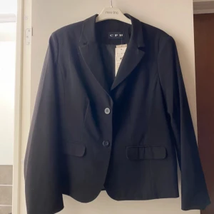 Svart kavaj - Snygg svart, helt oanvänd, kavaj i en kortare modell⭐️Den är i storlek 40 men är lite mindre i storleken, som en S/M. Passar även mig som vanligtvis har XS, blir lite boxigare och får plats med en stickad tröja under💕