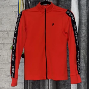 Peak Performance kofta - Röd och svart peak performance kofta utan luva (ficka på ryggen). Nytvättad, helt nytt skick, köpt på peak performance butiken. I storlek XS funkar även om du har storlek S.