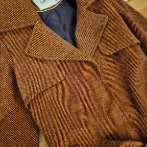 Brun kappa från Sarah L - Säljer en snygg brun kappa från Sarah Laurence, trenchcoat i mycket bra skick. Den har ett klassiskt snitt med ett bälte i midjan och långa ärmar. Fodret är mörkblått och ger en fin kontrast. Perfekt för höst och vår! Underbara höstfärger, rätt så unik! 