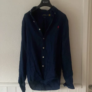Ralph Lauren skjorta  - Det är en mörkblå linneskjorta som är i nyskick. Andvänd Max 5 gånger och har inga spår av användning. Köpt på Zalando Pris kan diskuteras 