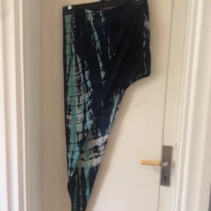 Mönstrad kjol från Shein - Säljer en cool mönstrad kjol från Shein. Den har ett unikt mönster i blått och grönt med en asymmetrisk design. Perfekt för att sticka ut på festen eller bara för en dag ute. Kjolen är i storlek XL och är superbekväm att ha på sig.