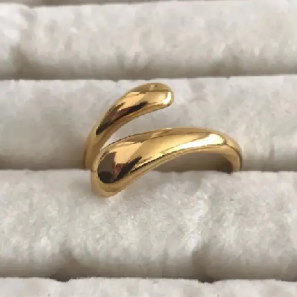 Säljer en superfin och elegant guldpläterad ring med en unik, böjd design. Den har en modern och stilren look som passar perfekt till både vardag och fest. Ringen är i nyskick och har en glansig yta som verkligen fångar ljuset.(89kr). Accessoarer.