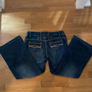 Wide/flared heans - Midrise wide/flared jeans i nyskick med broderier på bakfickorna Priset kan diskuteras