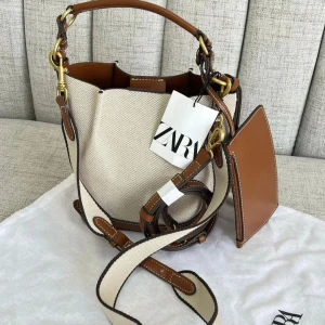 ZARA BAG - Väska i canvastyg med kontrasterande sömmar från Zara. Handtag och dubbla, justerbara och löstagbara axelremmar. Magnetknäppning. Slutsåld modell, nypris 379kr & fortfarande i nyskick.  Mått: 21x20.3x 12.3cm. 