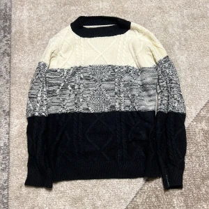 Svart och vit stickad tröja - Säljer en snygg stickad tröja i svart och vit med ett unikt mönster. Tröjan har långa ärmar och en rund halsringning. Perfekt för kyligare dagar!