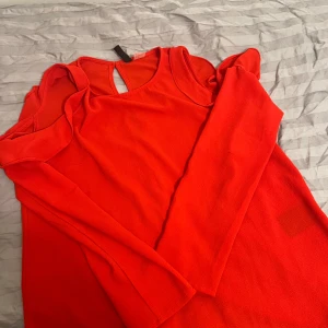 Röd topp med öppning i ryggen - Snygg röd topp med öppning i ryggen och uppe vid ärmarna. Den har användts endast ett få tal gånger. Går att klä upp eller ner. 
