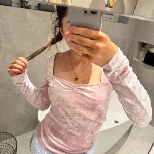 Rosa långärmad topp från & Other Stories - Säljer en söt rosa långärmad topp från & Other Stories. Toppen har en lätt glansig finish och en subtil rynkdetalj vid halsringningen. Perfekt för att lägga till en touch av elegans till din outfit. 💖