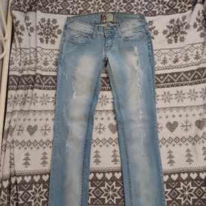 Super snygga ljusblå lowwaist jeans - Snygga ljusblå jeans från med coola slitningar. De har en klassisk femficksdesign och knappar i midjan. Inte mina bilder utan från tjejen jag köpte de från 