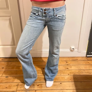 Ljusblå bootcut jeans - Snygga ljusblå bootcut jeans med låg midja och klassisk femficksdesign. Perfekta för en avslappnad stil. De har en dragkedja och knapp framtill.