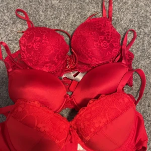 Röda spetsbehåar - Säljer flera röda behåar med spetsdetaljer. De har justerbara axelband och en elegant design. Perfekt för att lägga till en touch av färg och stil.