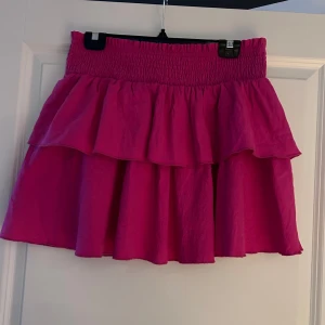 Rosa volangkjol - Säljer en söt rosa kjol från Shein med volangdetaljer. Kjolen har en elastisk midja för en bekväm passform. 