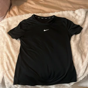 Svart tränings t-shirt från Nike - Säljer en svart t-shirt från Nike med korta ärmar och klassisk Nike-logga på bröstet. Perfekt för träning.