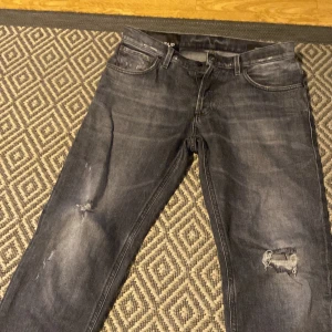 Grå jeans från Dondup - Snygga grå jeans från Dondup med slitna detaljer och en klassisk femficksdesign. Tillverkade i Italien med knappstängning och dragkedja. Perfekta för en avslappnad stil. Storlek 31 men passar som 32 riktigt heta. Bara o höra av sig! På o göra byten också hör av dig ba!