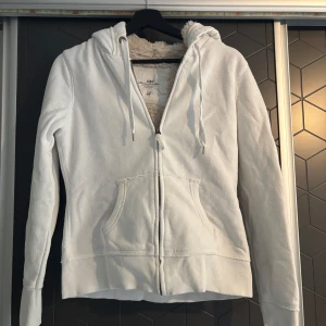 Vit hoodie med dragkedja - Säljer en vit hoodie från Hm i storlek  M. Den har en dragkedja framtill och en mysig fodrad insida. Perfekt för kyliga dagar. Hör av dig vid intresse! 🤍