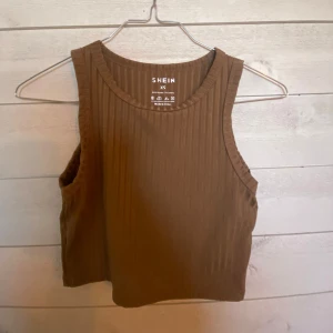 Brun ribbad linnetopp från Shein - Säljer en snygg brun ribbad linnetopp från Shein i storlek XS. Toppen är ärmlös och har en stilren design som passar perfekt till både vardag och fest. Perfekt för sommardagar eller som ett lager under en jacka.