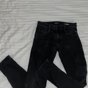Svarta jeans från Replay, modell anbass - Snygga svarta jeans från Replay med en klassisk femficksdesign. Jeansen är modell anbass. Perfekta för en stilren look.