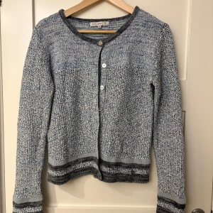 Blåmelerad kofta från Flash Woman - Säljer en snygg blåmelerad kofta från Flash Woman. Koftan har långa ärmar och knappar framtill. Perfekt för att hålla sig varm och stilren under kyligare dagar.