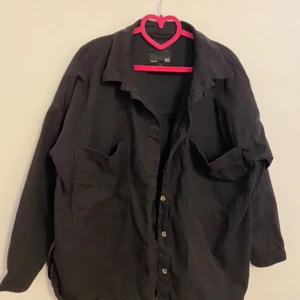 Svart overshirt från 157 - Säljer en svart overshirt/jacka från 157 i storlek XL. Passar bra i ljummet väder. Avslappnad passform med knappar framtill samt två stora fickor. Perfekt för lager-på-lager-stil och passar till många olika outfits!🌸
