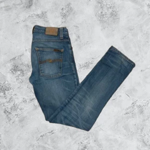Blå jeans från Nudie Jeans - Säljer ett par snygga blå jeans från Nudie Jeans. De har en slim passform och klassisk femficksdesign. Perfekta för en stilren look.
