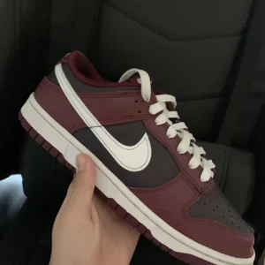 Nike Dunk Retro i vinrött och vitt - Snygga Nike Dunk Retro sneakers i vinrött och vitt. Skorna har en klassisk design med vit sula och snörning. Vid flera bilder eller frågor skriv till mig i DM