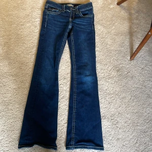 Mörkblå bootcut jeans från Gina Tricot - Snygga mörkblå bootcut jeans från Gina Tricot med klassisk femficksdesign och kontrastsömmar. Perfekta för en avslappnad stil med en touch av retro. Passar bra till både sneakers och klackar.