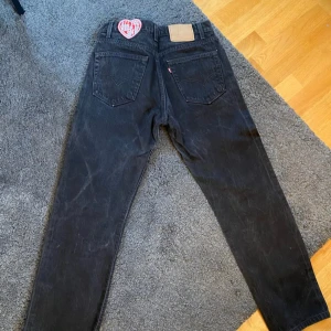Svarta jeans från Levi's DIY - Snygga svarta Levi's jeans med klassisk design och röd etikett. De har en rak passform och är perfekta för en stilren look. Jeansens mörka färg gör dem lätta att matcha med olika outfits.
