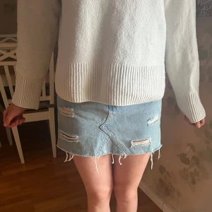 Blå jeanskjol med slitningar  - Snygg blå jeanskjol från Sinsay med slitna detaljer och fransig nederkant. Köpt utomlands, storlek xs! Säljer då den inte passar mig längre! Är sååååå snygg till en stickad törja en sommarkväll💘 pris kan diskuteras vid snabb affär 🩷 hör av dig vid minsta lilla fundering!