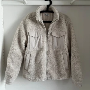 teddyjacka från These Glory Days - Säljer en mysig Crèmefärgad teddyjacka från These Glory Days i storlek medium. Perfekt för våren och lite varmare vinter dagar. Använd bara 3-4 ggr