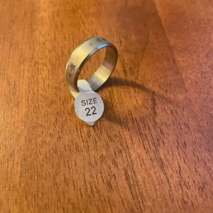 Silverfärgad ring med stjärnmönster - Snygg silverfärgad ring med ingraverade stjärnor runt om. Perfekt för att ge en subtil men stilren touch till din outfit. Passar både till vardag och speciella tillfällen.