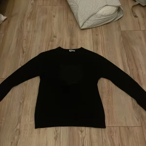 Svart tröja från Kenzo med tigerbroderi - Säljer en svart tröja från Kenzo med ett coolt tigerbroderi på framsidan. Tröjan har långa ärmar och en normal passform. Perfekt för dig som vill ha en stilren men ändå iögonfallande look.