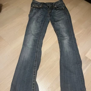 Miss Me jeans - Snygga Miss Me jeans med unika dekorativa sömmar och detaljerade bakfickor. Byxorna har en klassisk femficksdesign och är perfekta för en trendig look. Passar bra till både vardag och speciella tillfällen. De är low waist och bootcut.