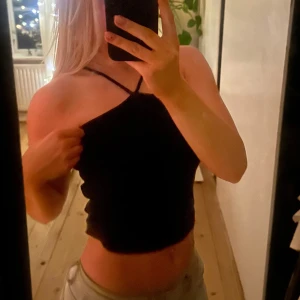 Svart topp - Snygg svart topp med smala band som korsar över axlarna. Perfekt för en stilren och modern look. Toppen är tight och passar bra till både jeans och kjol.