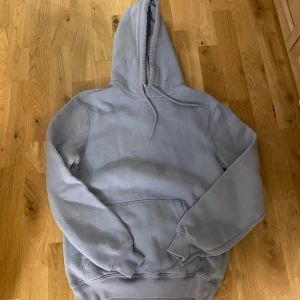 Ljusblå hoodie från H&M - Säljer en ljusblå hoodie från H&M i relaxed fit. Perfekt för en avslappnad stil med sin mjuka och bekväma design. Den har en klassisk huva och ribbade muddar vid ärmslut och nederkant. Använd några gånger