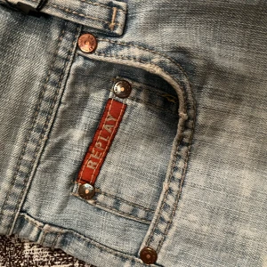 Lågmidjade bootcut jeans - Jättesnygga lågmidjade jeans med slitningar från replay💞💞 midjemått: 35cm innebenslängd:81cm.
