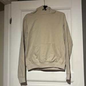 Beige hoodie från Gildan - Säljer en stilren beige hoodie från Gildan. Den har en praktisk magficka och en bekväm huva. Perfekt för en avslappnad stil.