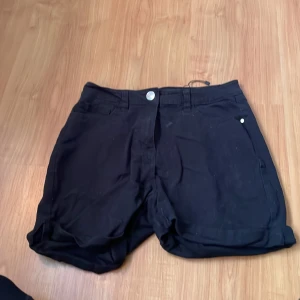Svarta shorts med knapp och dragkedja - Snygga svarta shorts med knapp och dragkedja framtill. Perfekta för en avslappnad stil. De har en klassisk design med fickor på sidorna.